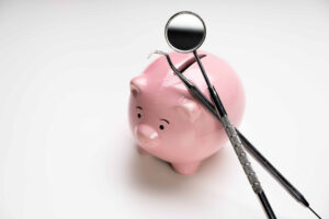 ピンクの豚の貯金箱に歯の治療器具が置かれている