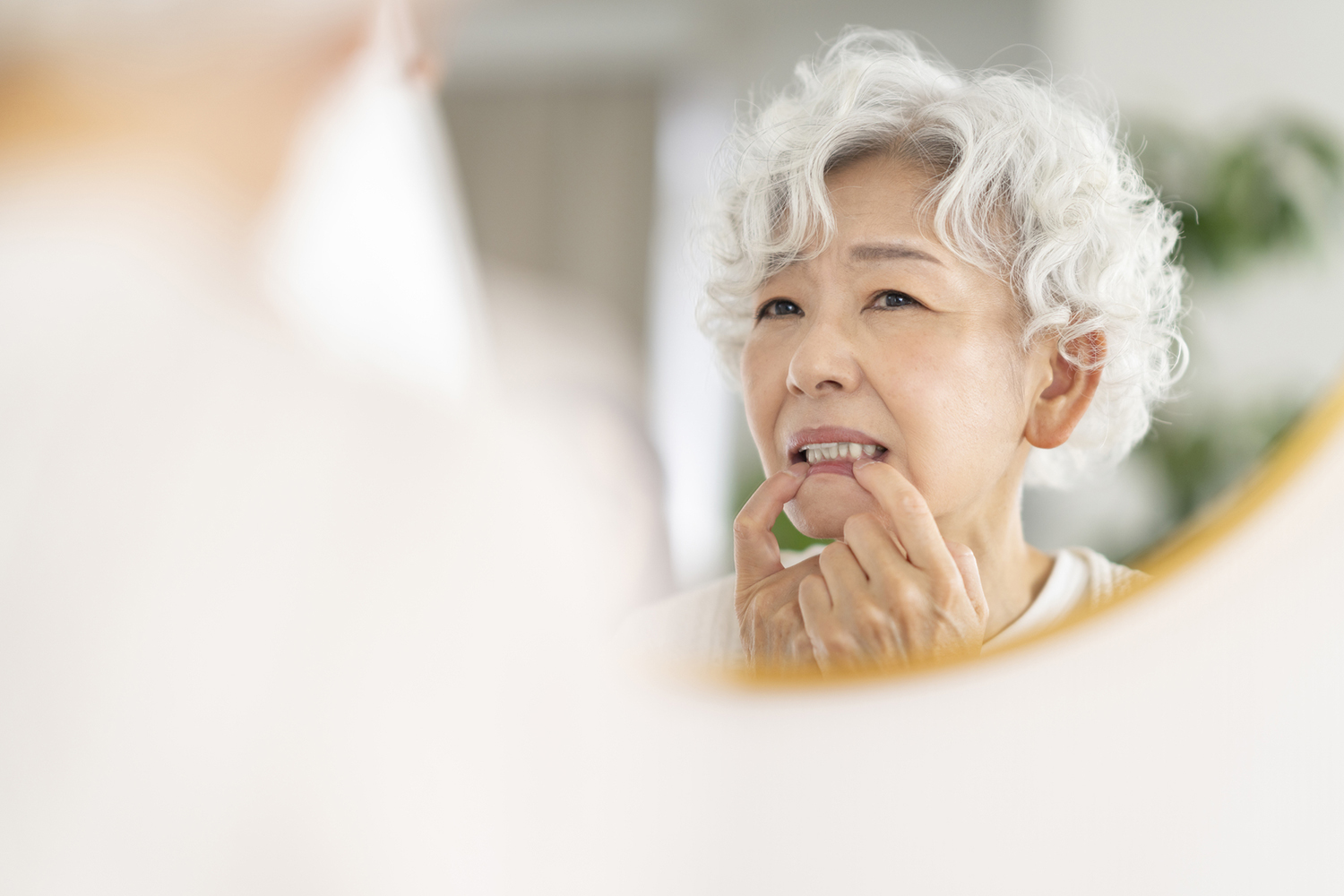 入れ歯が痛くて鏡を見る女性
