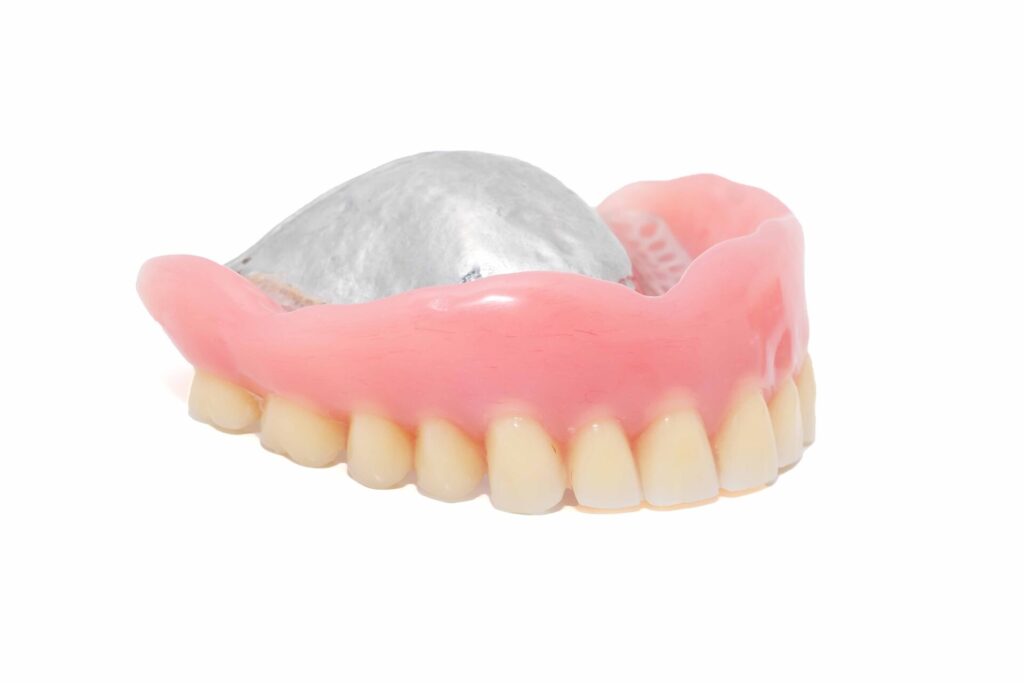 白い背景の前に上の歯の入れ歯が置かれている