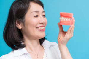 歯の模型を片手に笑顔の女性