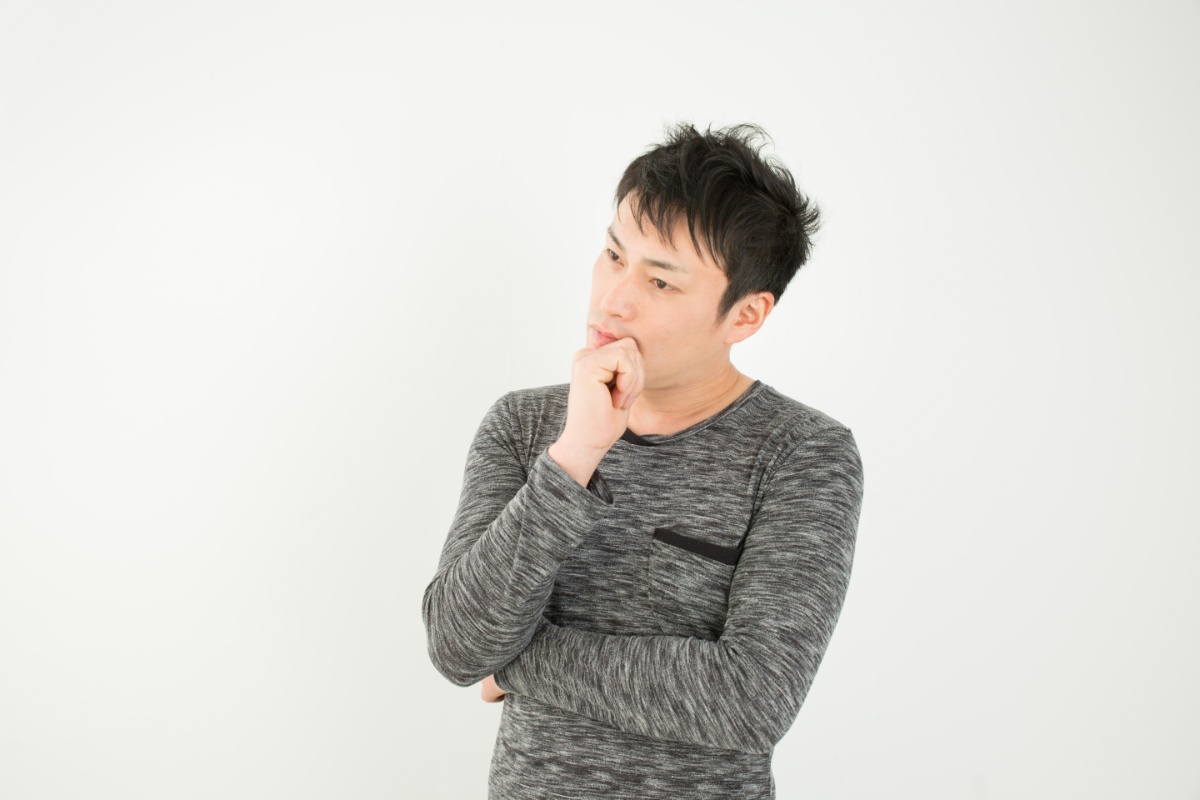 首をかしげ悩んでいる男性