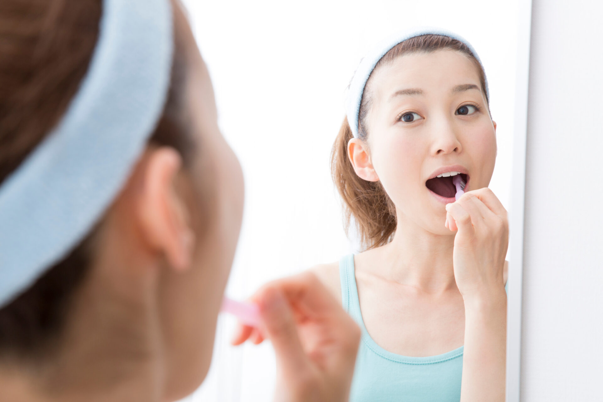 鏡を見て丁寧に歯磨きする女性