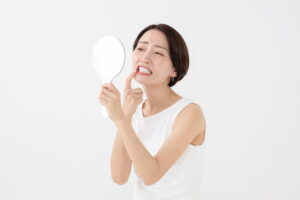 歯と歯の間の虫歯を早期に発見するためにセルフチェックをする女性