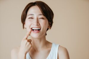 セラミック治療で白くなった歯を指さし嬉しそうな女性