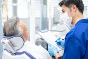 インプラント治療後に痛みが出て歯科医の診察を受ける男性