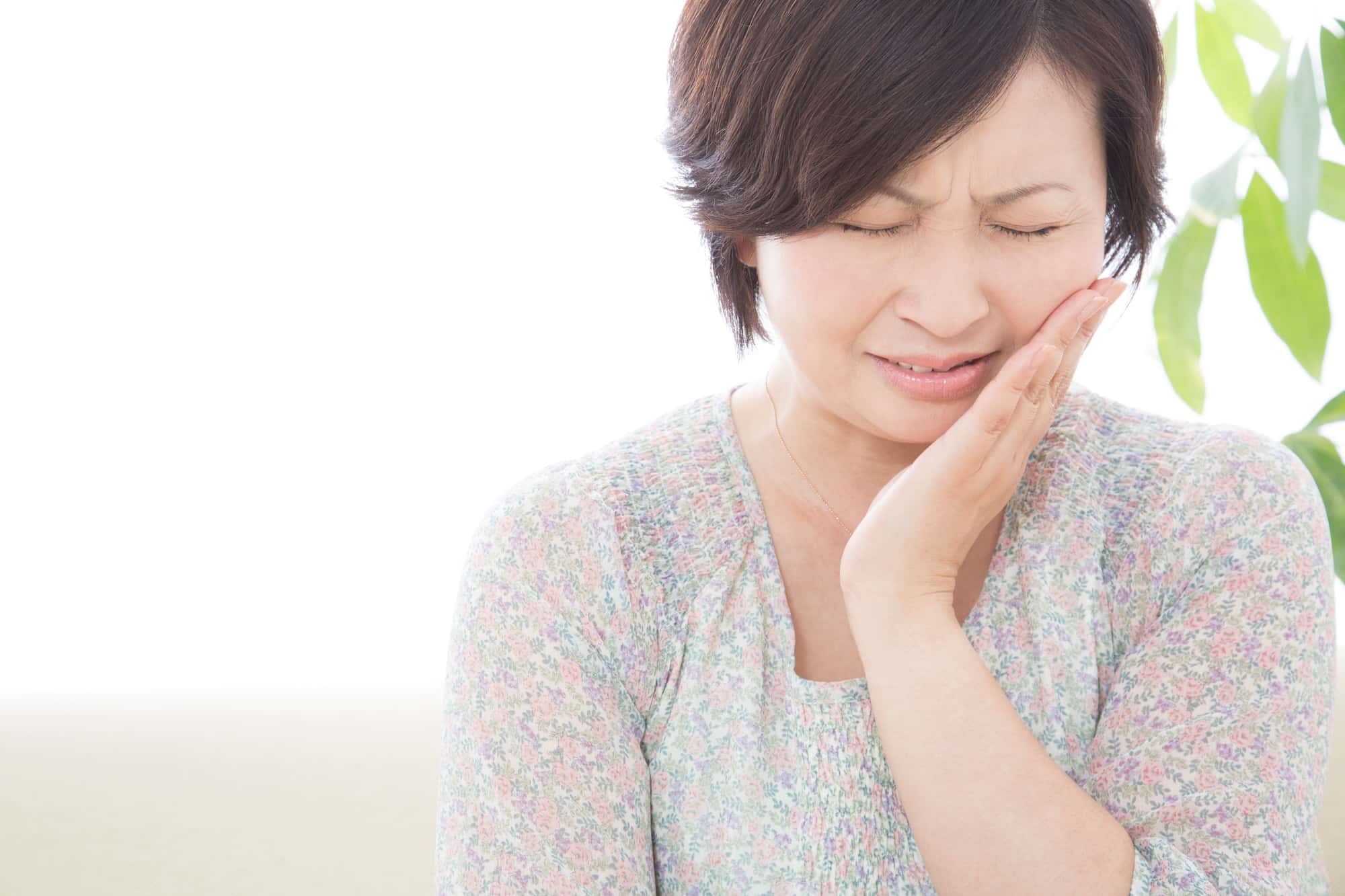インプラント治療で痛みを感じて頬をおさえる女性